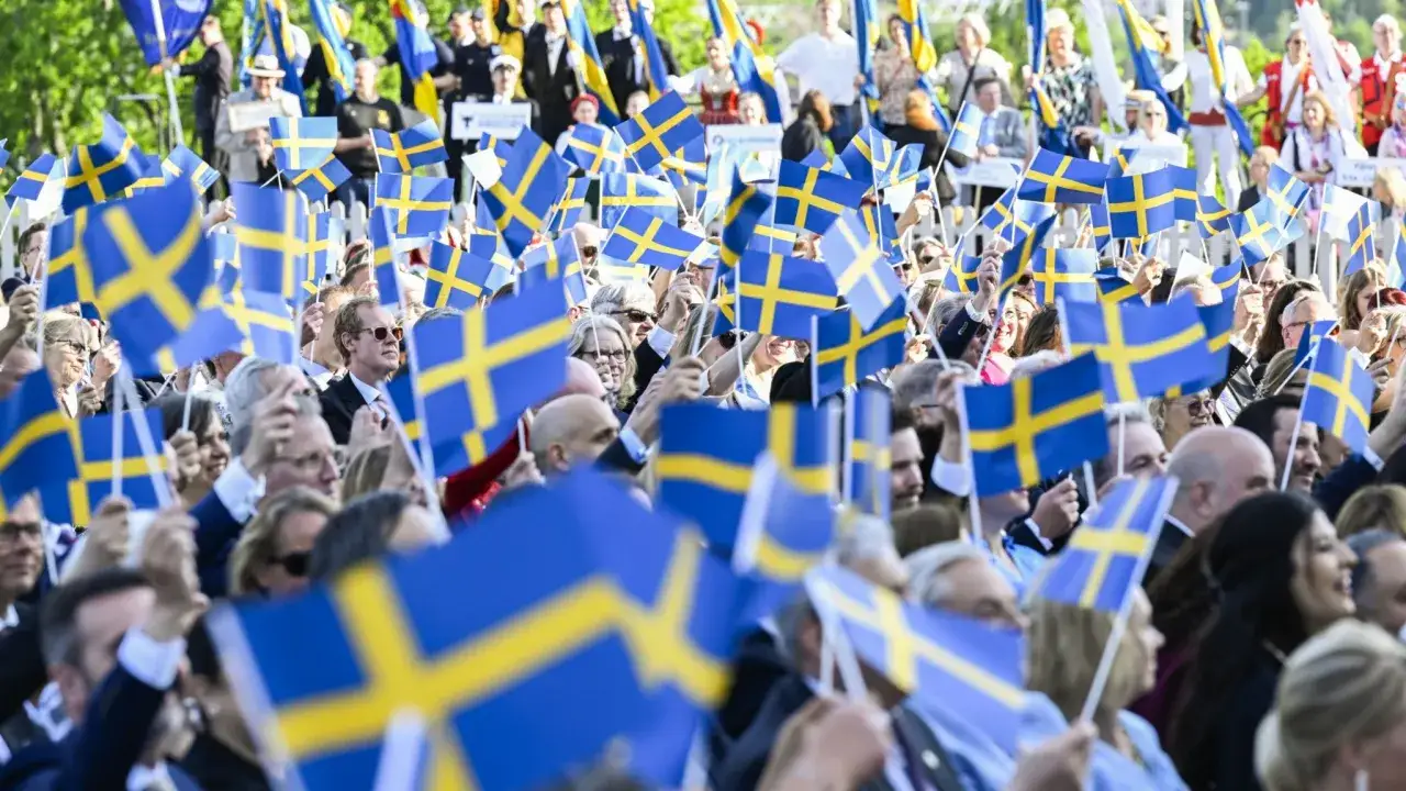 Folk viftar med svenska flaggor under firandet av Sveriges nationaldag.