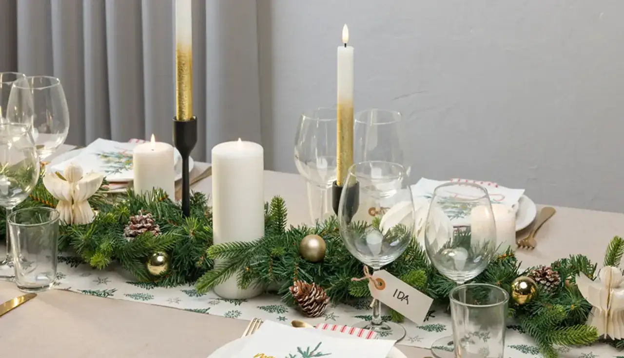En modern juldukning med granris, ljus, julgranskulor och änglar. Ett vackert bord för en mysig jul.