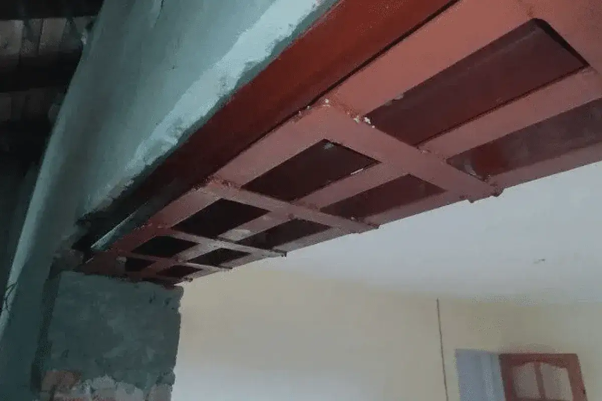 Metalowa konstrukcja pod sufitem, wykonana jako podciąg zamiast ściany nośnej, wsparta na ceglanym słupku.