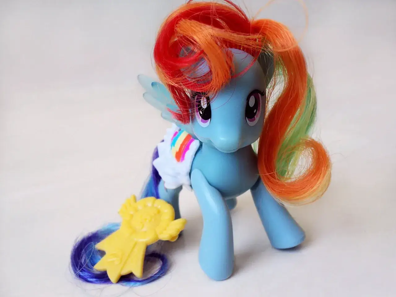 Niebieski kucyk Rainbow Dash z tęczową grzywą i ogonem, z żółtą nagrodą. Idealny do zabawy w
