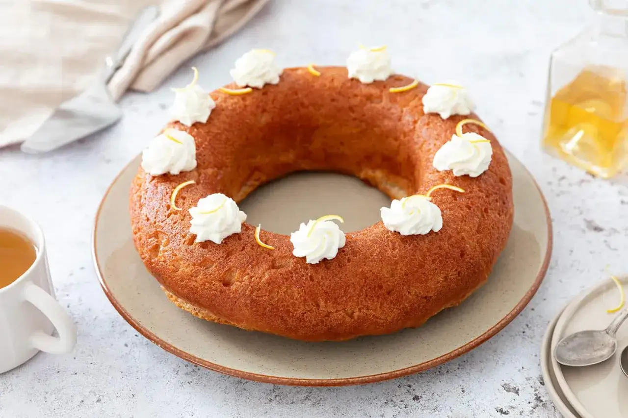 Un baba au rhum moelleux, d&eacute;cor&eacute; de cr&egrave;me fouett&eacute;e et de zestes de citron, pr&ecirc;t &agrave; &ecirc;tre d&eacute;gust&eacute;.