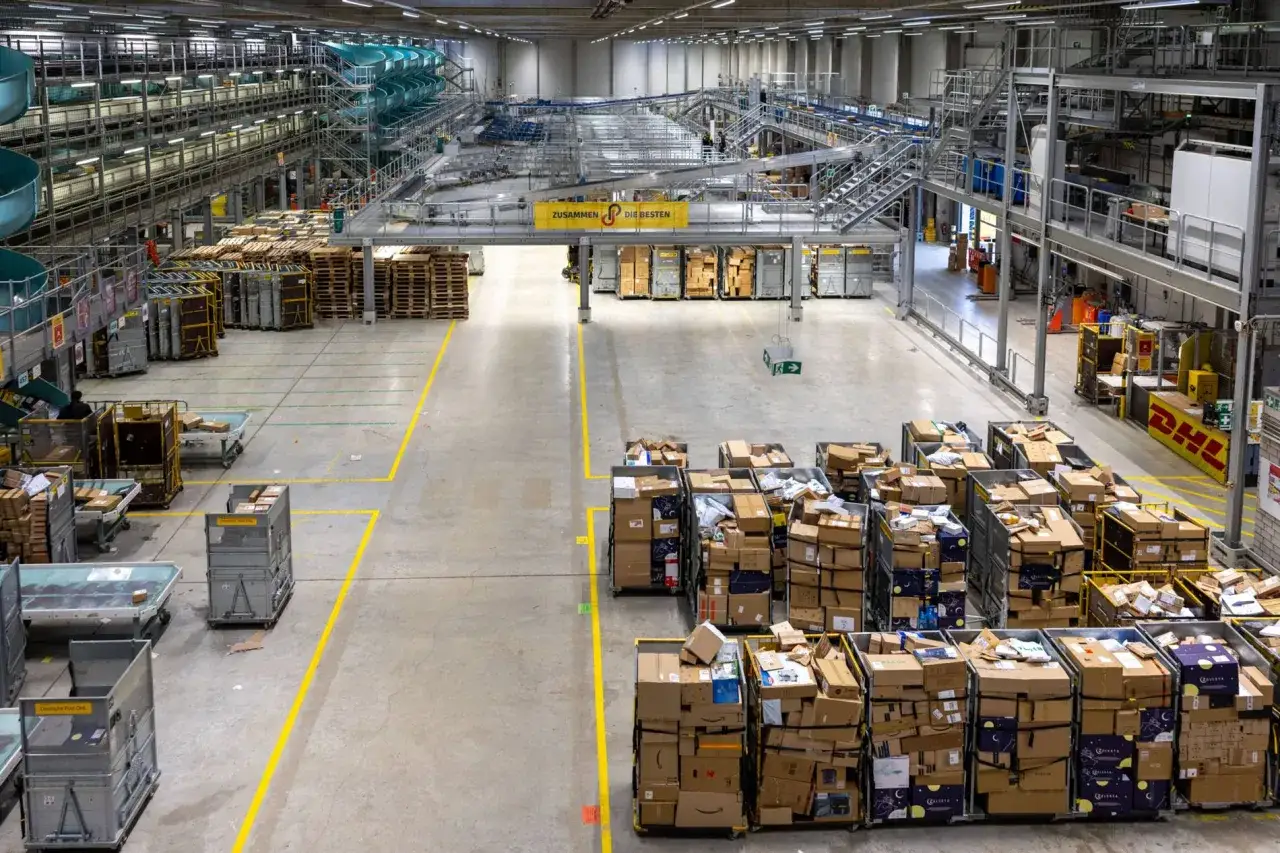 Großes DHL Verteilzentrum mit vielen Paketen, Sortieranlagen und Paletten.