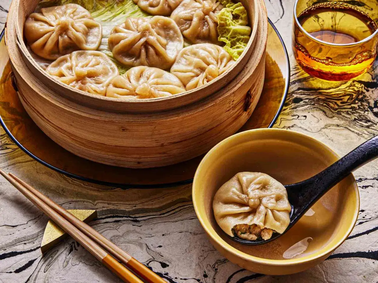 &Aring;ngkokta dumplings i bambukorg, en perfekt inspiration f&ouml;r ditt n&auml;sta dumplings recept. En sked visar en dumpling med fyllning.