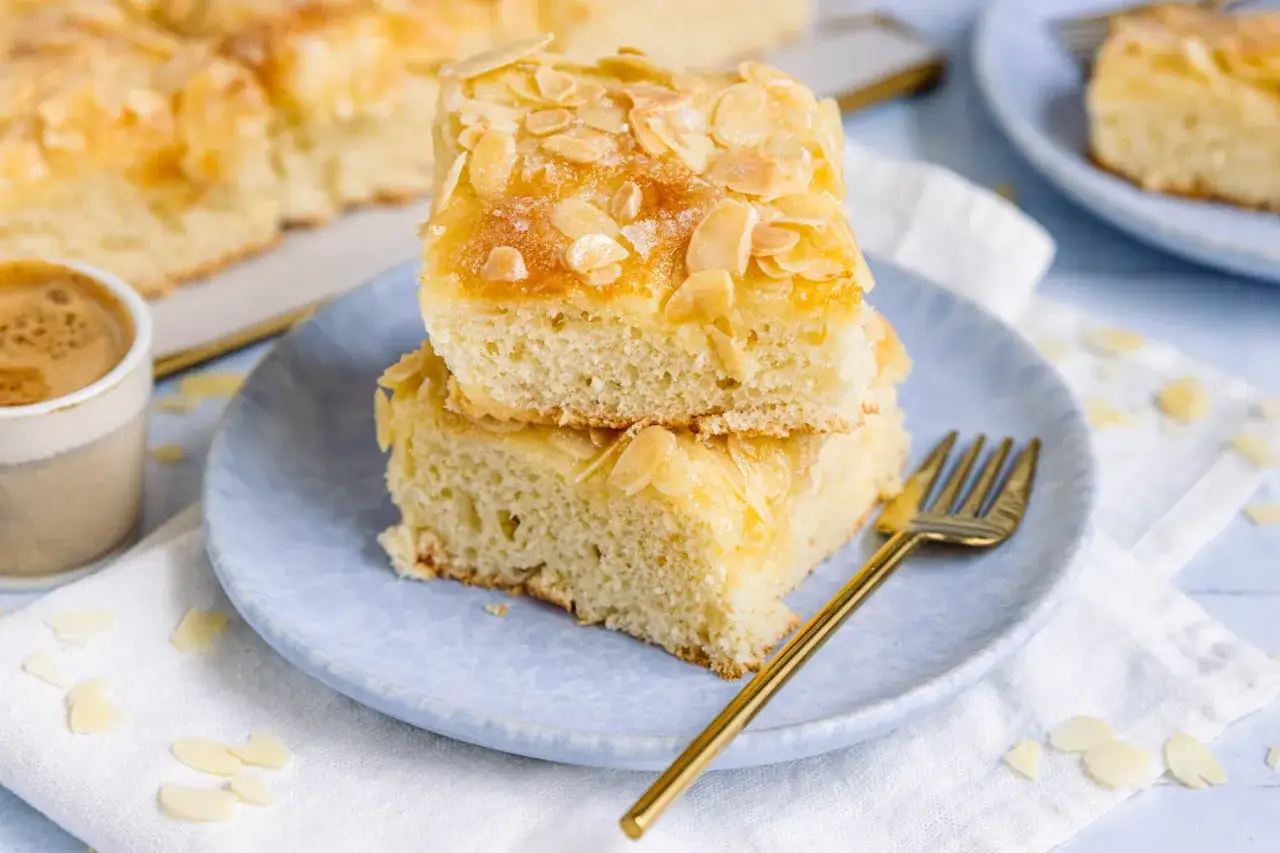 Zwei St&uuml;cke Butterkuchen mit Mandelbl&auml;ttchen, serviert mit Kaffee. Ein k&ouml;stliches butterkuchen rezept zum Genie&szlig;en.