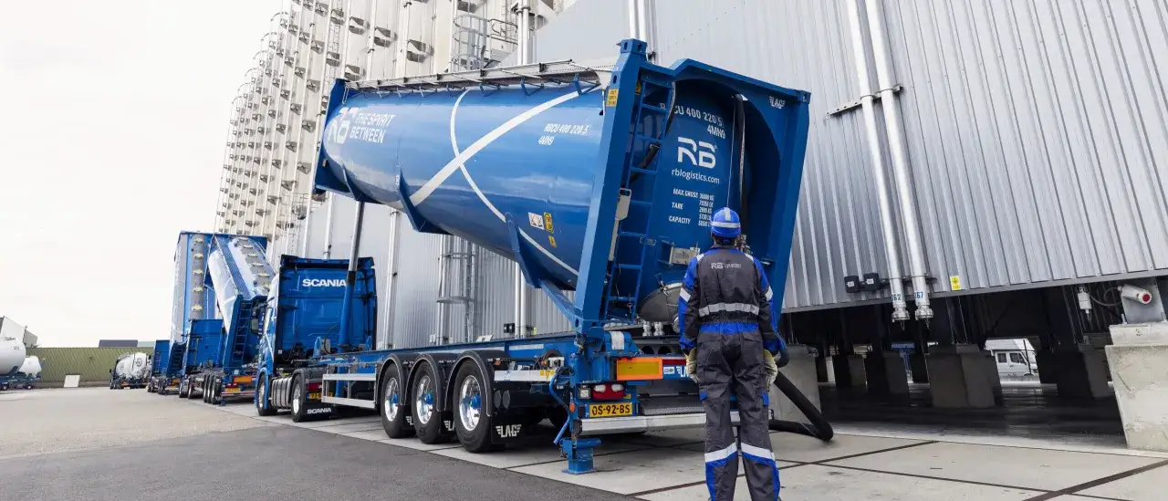 Ein Mann in Arbeitskleidung steht vor einem blauen Tankwagen. Dies ist ein Beispiel f&uuml;r einen **Bulk**-Container, der f&uuml;r den Transport von Sch&uuml;ttg&uuml;tern verwendet wird.