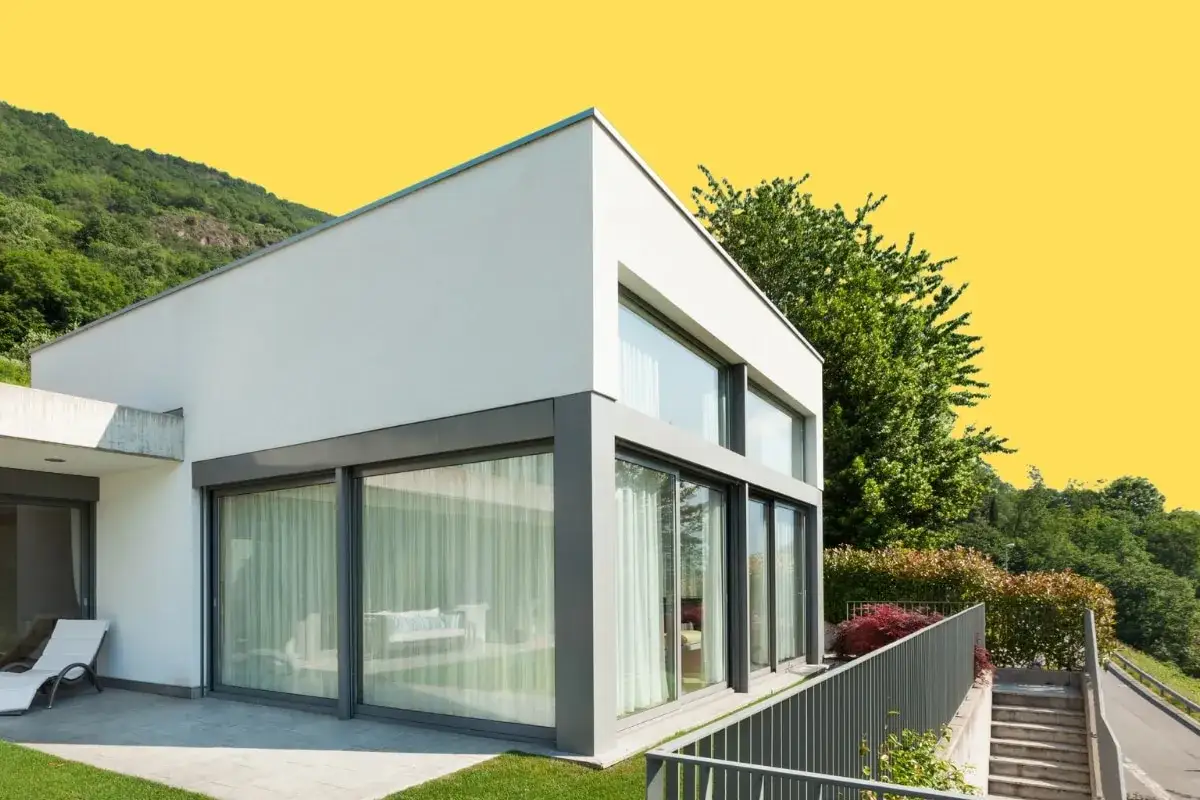 Casa moderna con paredes prefabricadas exterior, grandes ventanales y vistas a la montaña.
