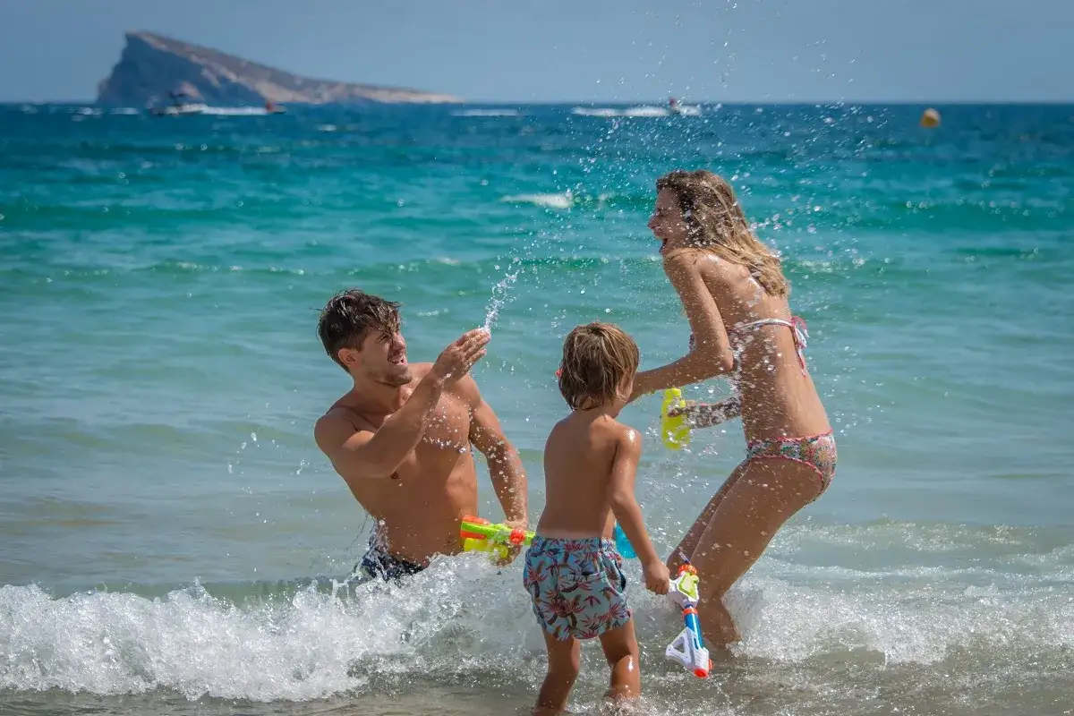 Familia divirtiéndose en el mar con pistolas de agua. ¡Una idea genial de qué hacer en Benidorm con niños!
