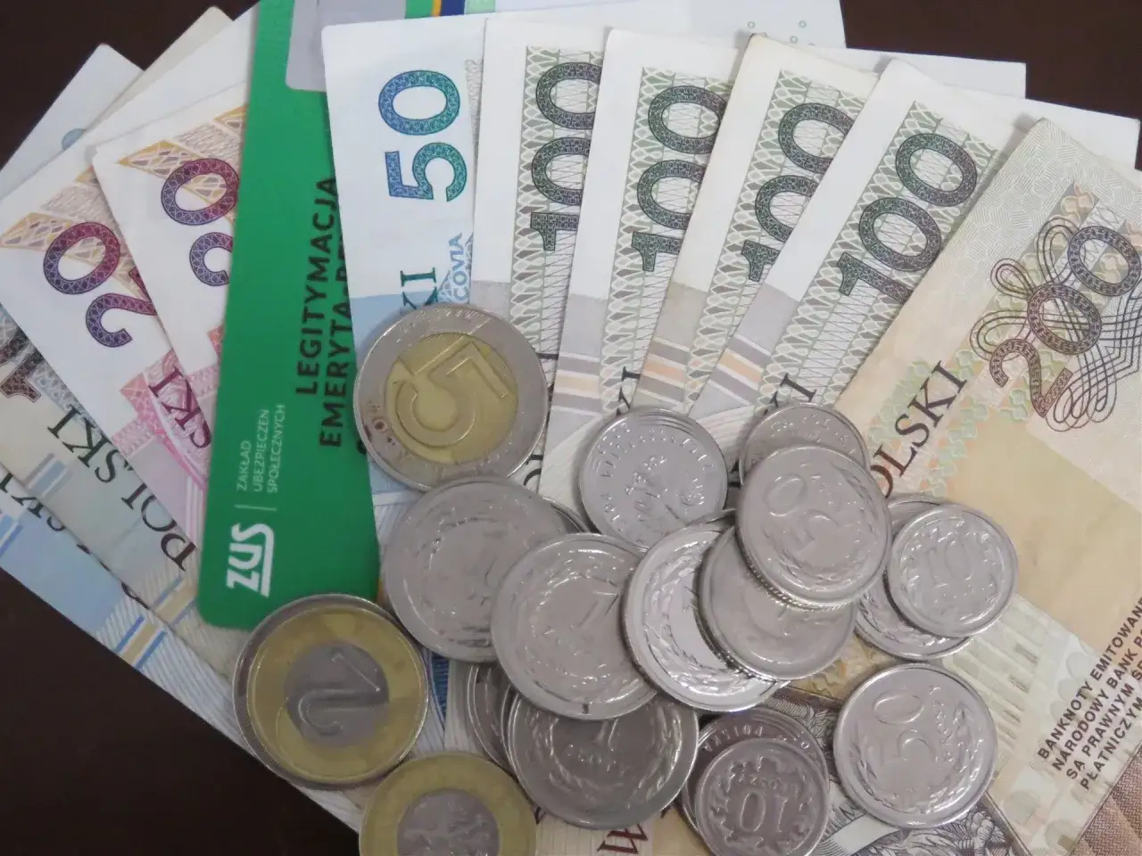 Pieniądze i monety na tle legitymacji emeryta. Tabela 13. emerytura 2026.