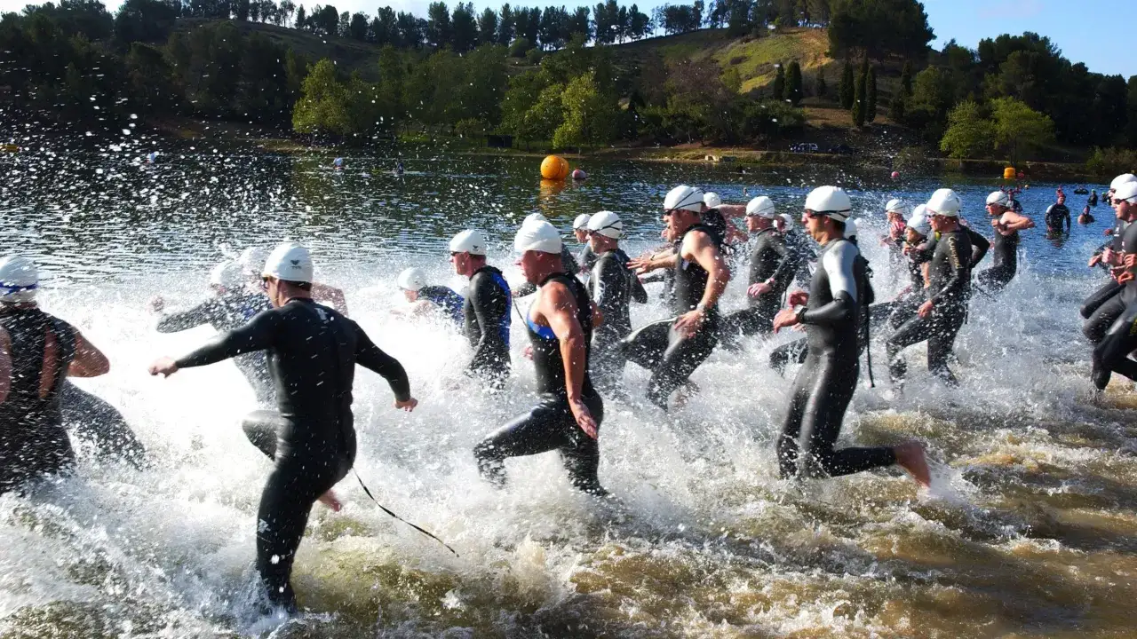 Triathleten im Neoprenanzug starten einen Sprint-Trainingslauf ins Wasser.