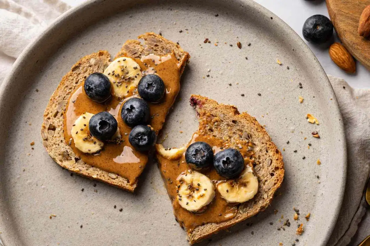 Tartines de pain complet avec beurre d'amande, bananes et myrtilles. Une collation parfaite pour la prot&eacute;ine avant de dormir.