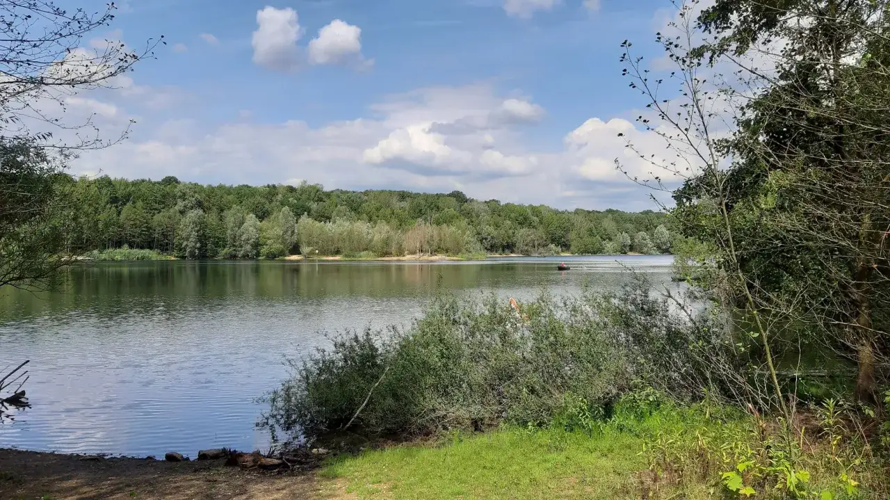 Idyllischer See mit Uferbewuchs und einem Boot, ideal f&uuml;r Wassersport am ASV Bensberg.