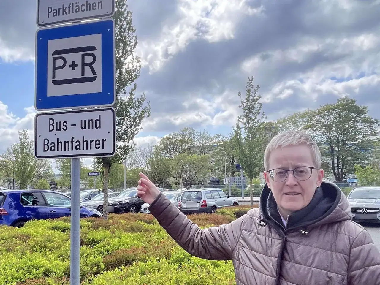 Frau zeigt auf ein Parkplatzschild mit