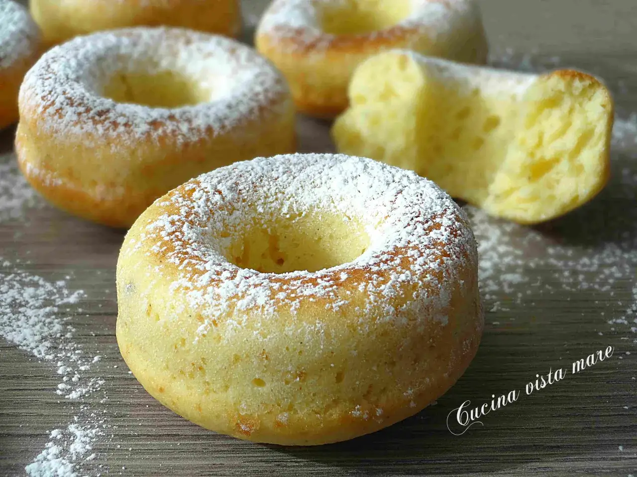 Ciambelle al forno soffici e dorate, cosparse di zucchero a velo. Una delizia fatta in casa, perfetta per la colazione o la merenda.