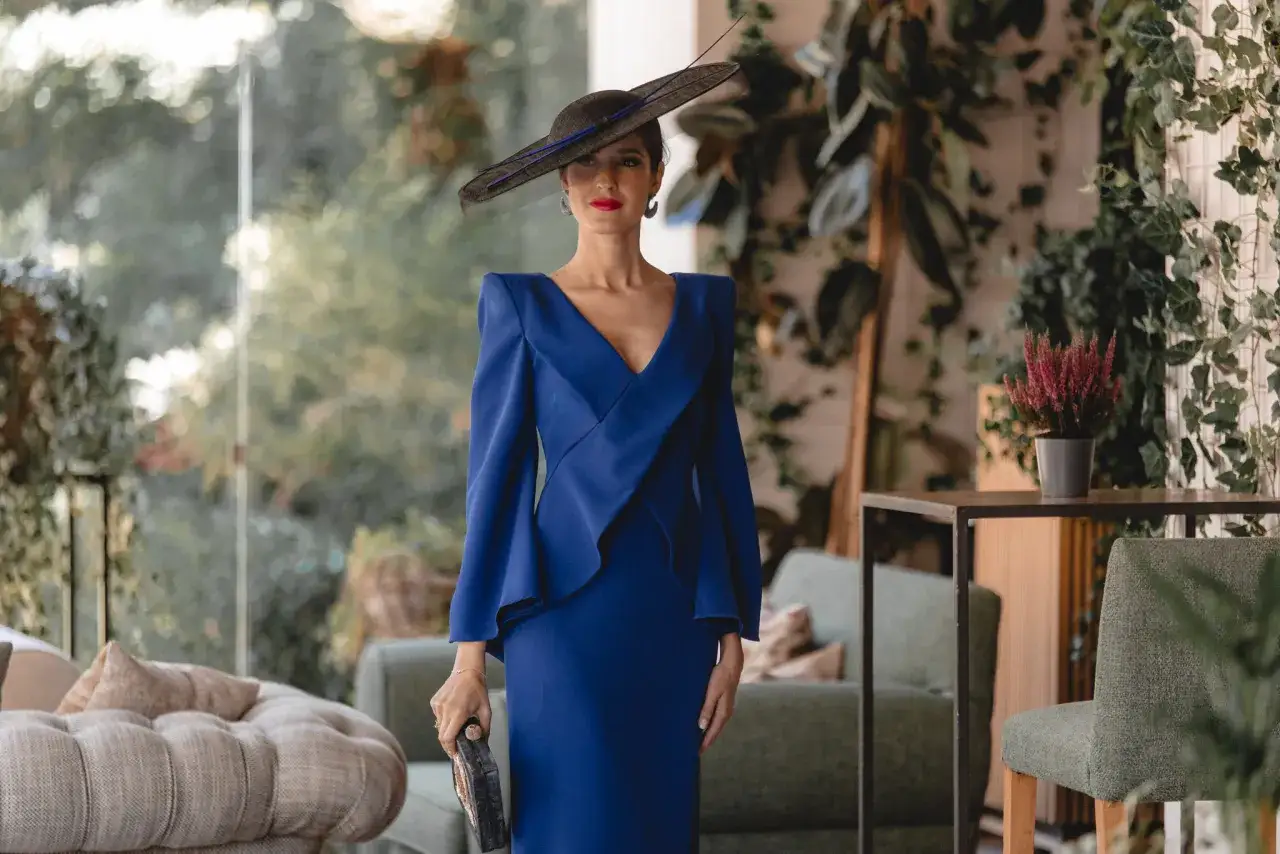 Elegante mujer con vestido azul klein, sombrero y bolso, ideal para saber como combinar un vestido azul klein para una boda.