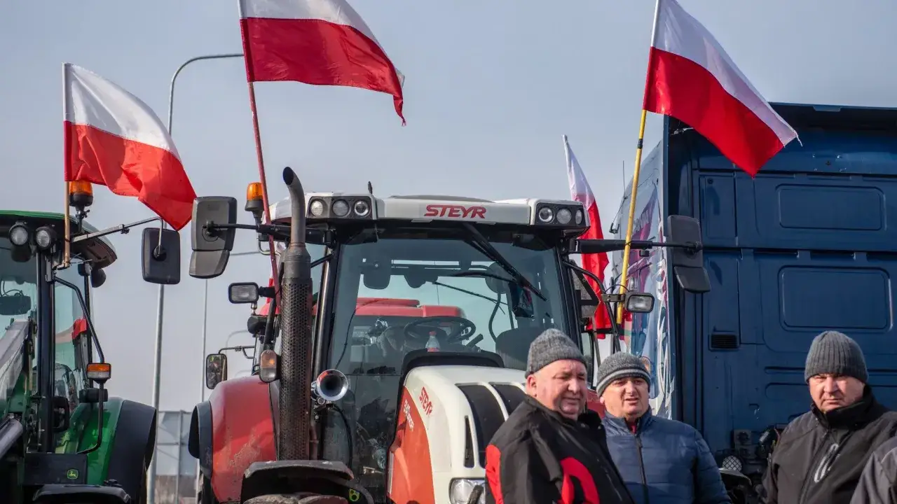 Rolnicy demonstrują, pytając: zielony ład o co chodzi? Na zdjęciu traktory i ciężarówka z polskimi flagami.