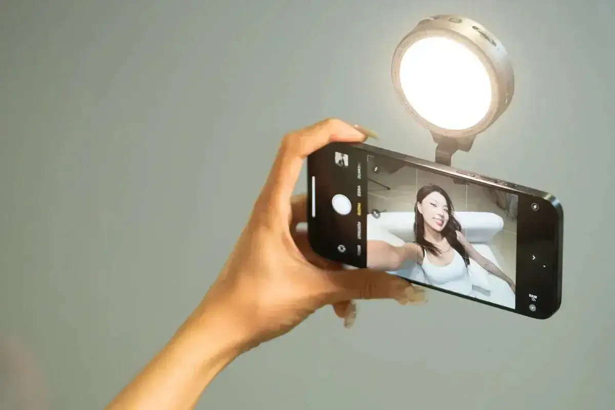 Uśmiechnięta dziewczyna robi sobie selfie z lampą pierścieniową.