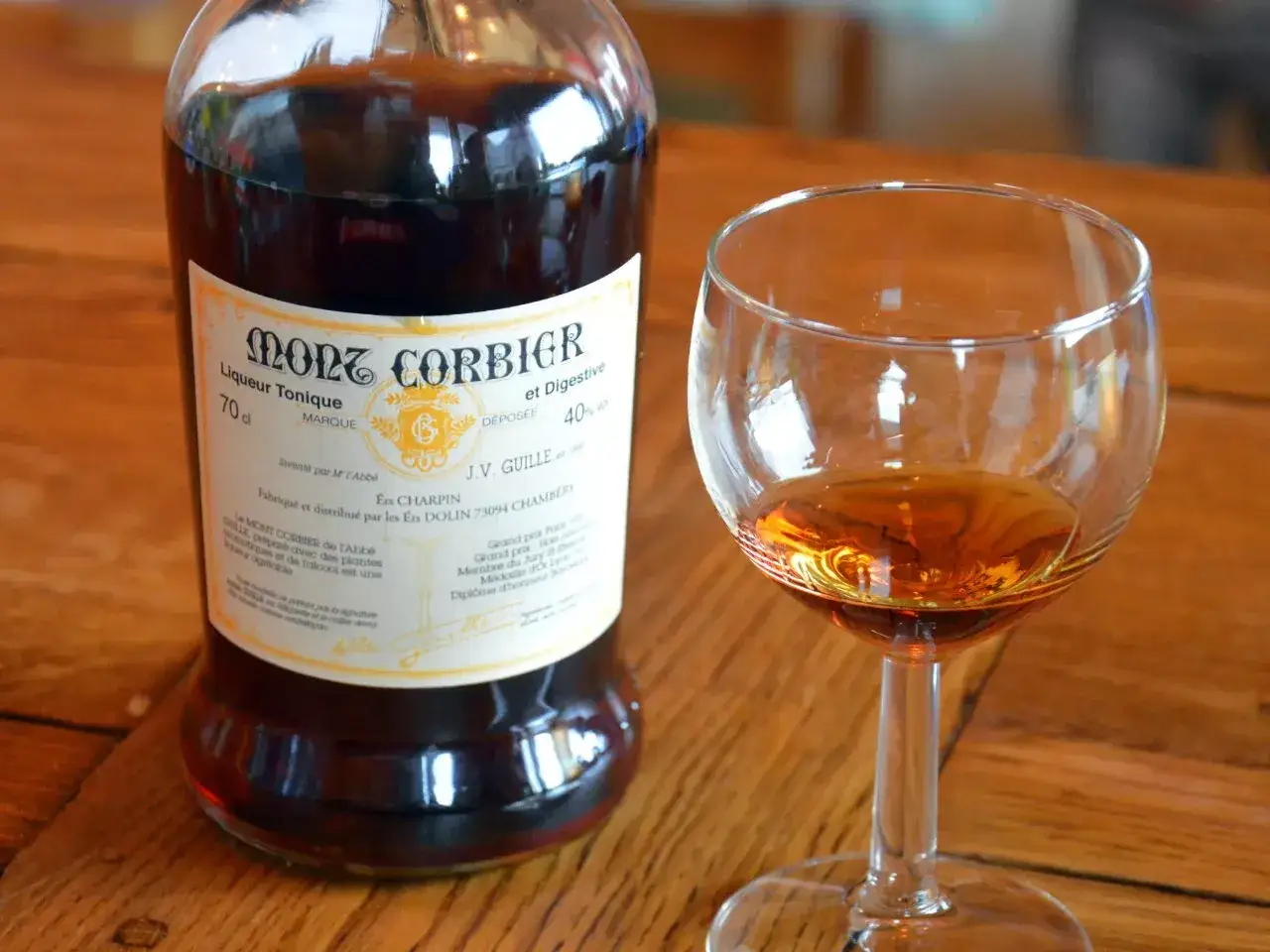 Une bouteille de Mont Corbier, liqueur tonique et digestive, &agrave; c&ocirc;t&eacute; d'un verre rempli de ce digestif alcool.