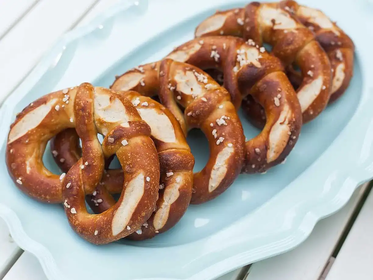 En ljusblå bricka med flera gyllenbruna kringlor, strösslade med grovt salt. Perfekt för fika.