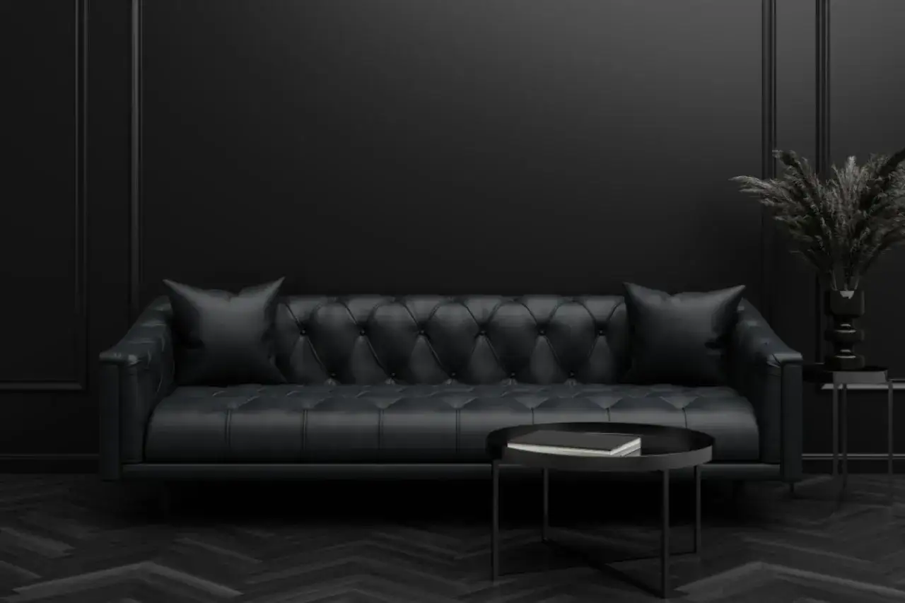 Elegante schwarze Ledercouch mit zwei Kissen und einem runden Couchtisch. Die Frage, welche Farbe passt zu Schwarz, wird hier eindrucksvoll beantwortet: Schwarz selbst!