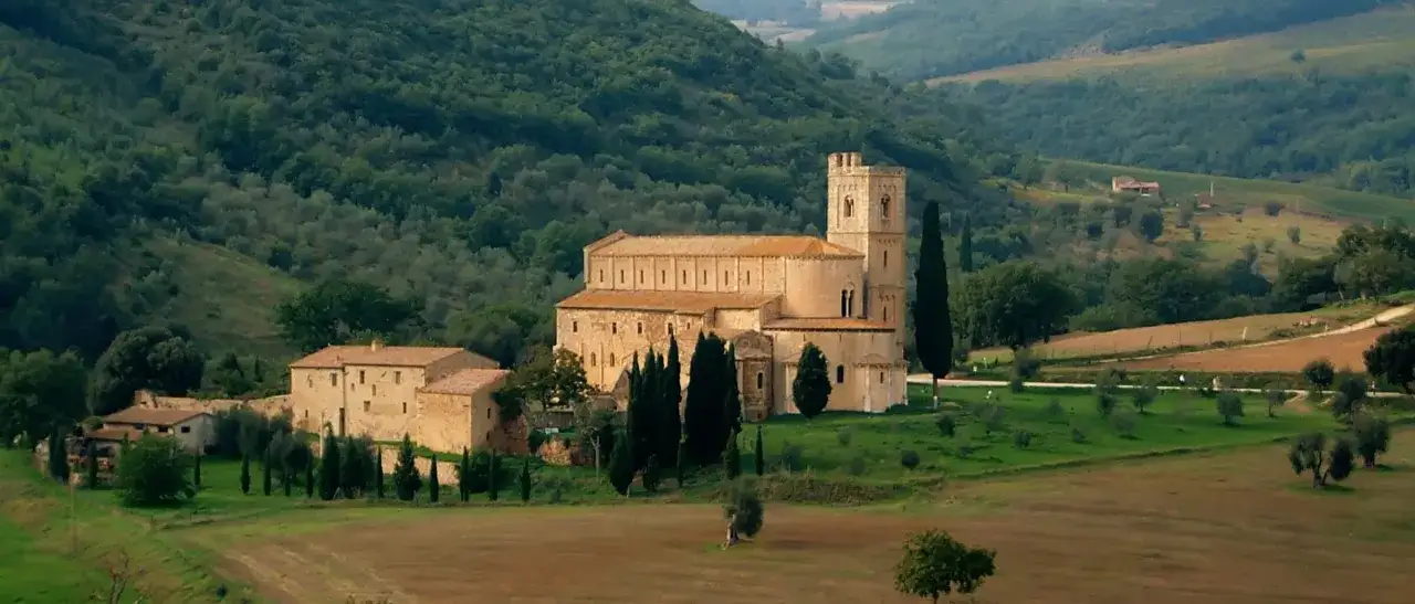 Ancient stone monasteries in Italy nestled in rolling green hills, a timeless landscape.