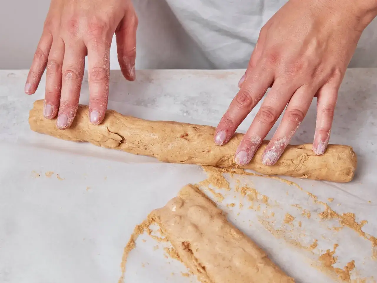 H&auml;nde formen Teig zu einer Rolle f&uuml;r ein Cantuccini Rezept.
