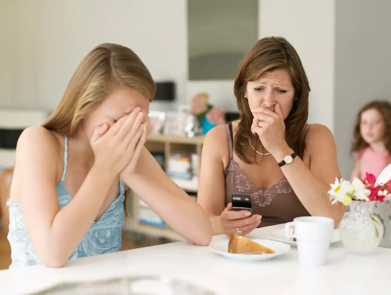 Zwei Frauen weinen, eine hält ein Handy. Sie können nicht alleine sein, die Nachricht ist traurig.