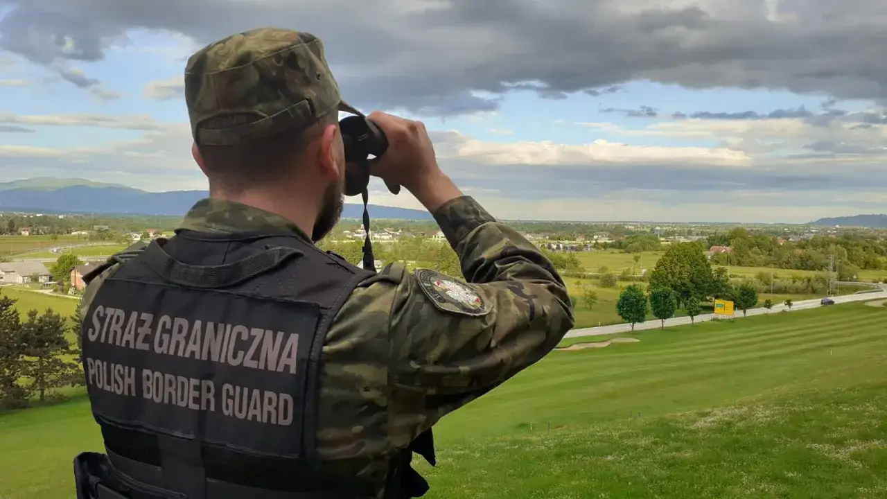 Strażnik graniczny obserwuje teren przez lornetkę. Zarobki w straży granicznej są adekwatne do odpowiedzialności.