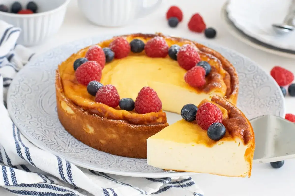 Deliciosa tarta de yogur griego, decorada con frambuesas y arándanos frescos. Una rebanada ya servida.