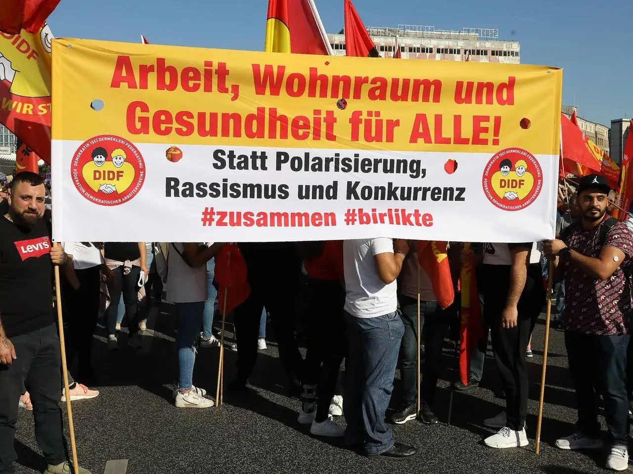 Menschen demonstrieren f&uuml;r Arbeit, Wohnraum und Gesundheit. Sie rufen 