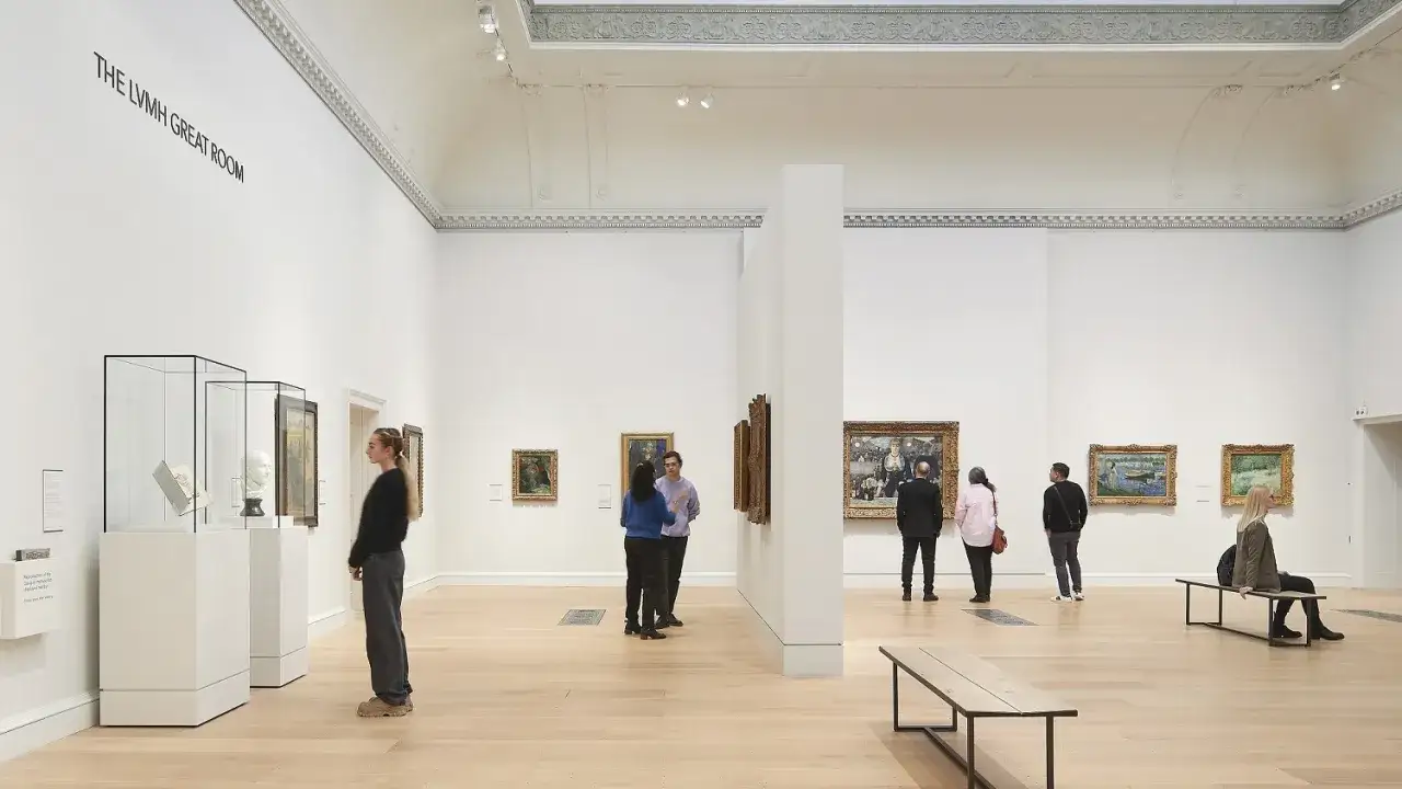 Visitors admire art in the LVMH Great Room. A young woman, perhaps Guy Hepner, stands by display cases.