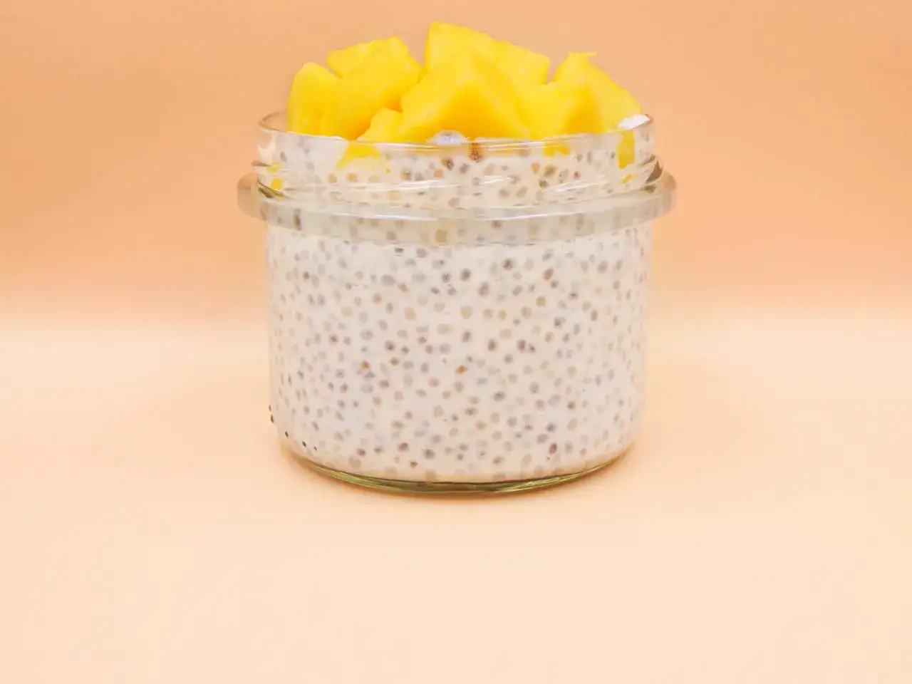 Pyszny deser z chia i bananem w słoiczku, zwieńczony kostkami mango.