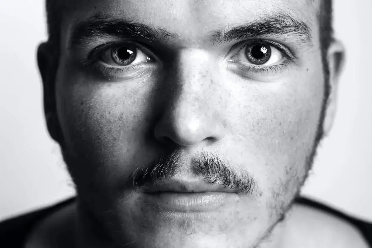 Gros plan sur le visage d'un homme aux yeux intenses et &agrave; la moustache fine.