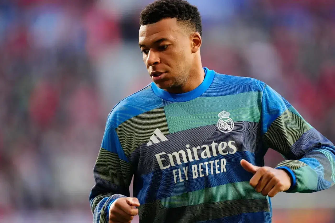 Mbappé, młody piłkarz w niebieskiej bluzie z herbem Realu Madryt i logo Emirates.