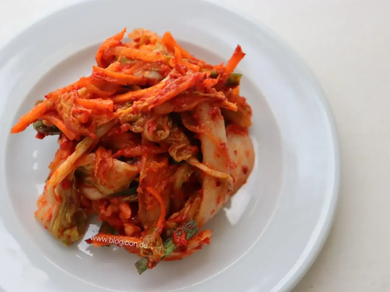 Würziges Kimchi, zubereitet nach einem authentischen kimchi rezept original, auf einem weißen Teller.