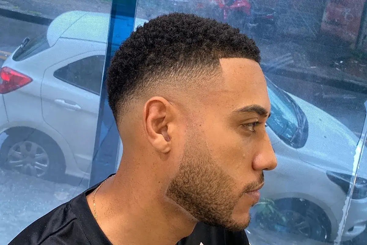 Hombre con corte de pelo moderno y barba con un degradado impecable.