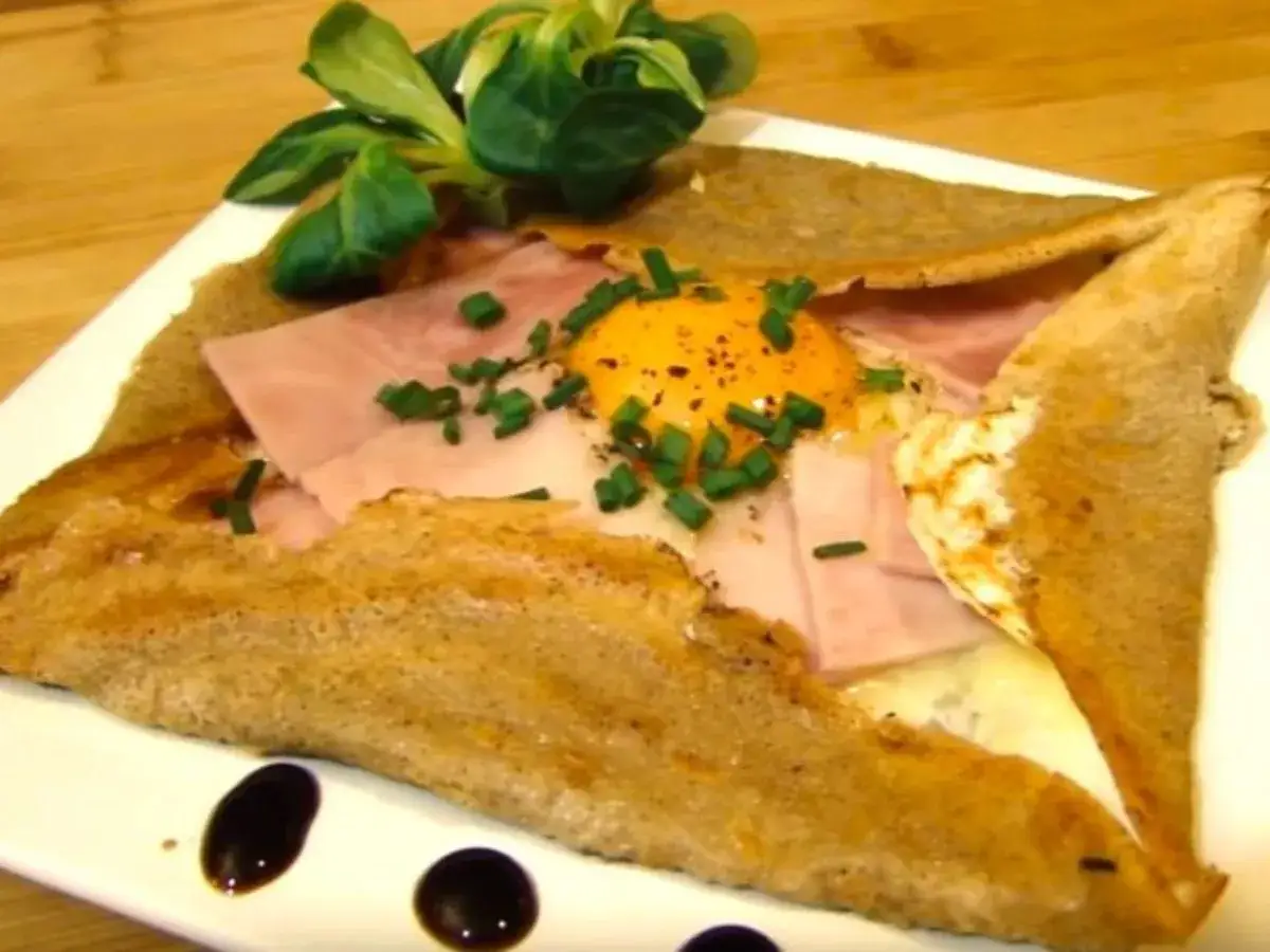 Galette de sarrasin garnie d'un œuf, de jambon et de ciboulette, un délice de crêpes françaises.