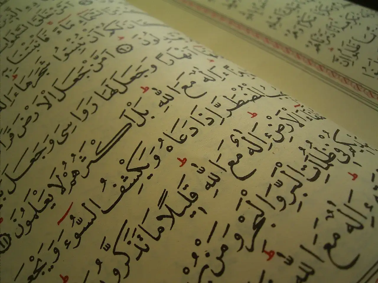 Nahaufnahme einer geöffneten Seite mit arabischer Schrift, die den Yasin Sura zeigt. Die Seiten sind leicht vergilbt, die schwarze Tinte ist deutlich lesbar.