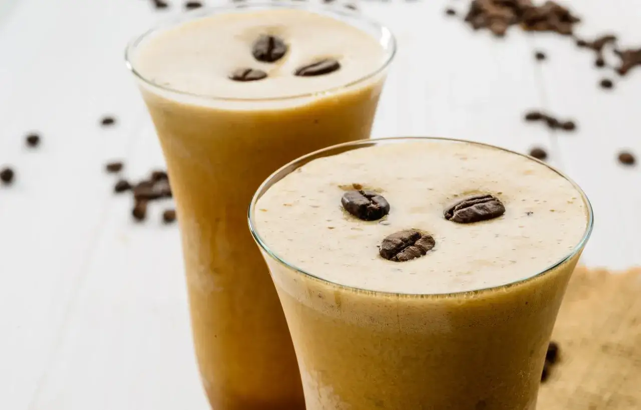 Dwa orzeźwiające napoje caffe freddo z pianką i ziarnami kawy na białym tle.