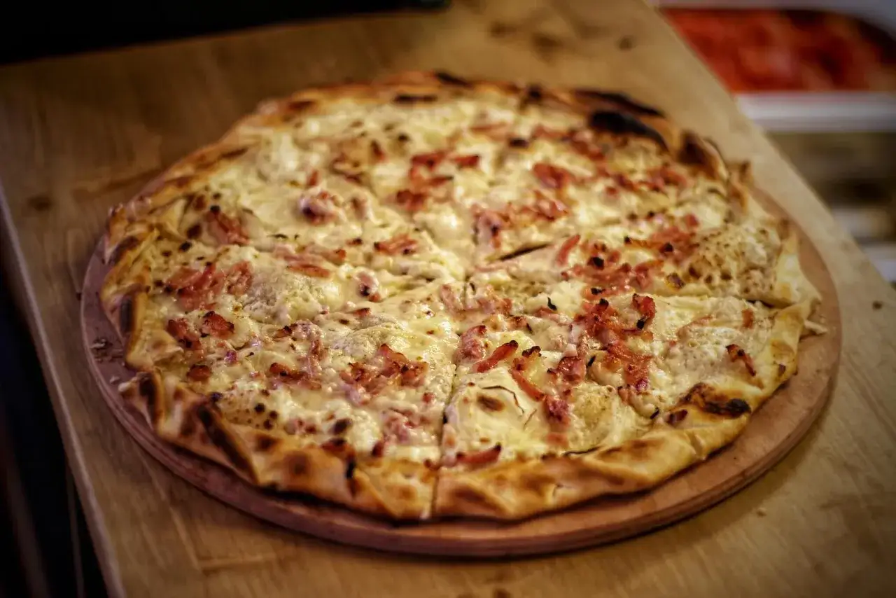 Tarta flambée con queso y tocino, ideal para comer barato en París.