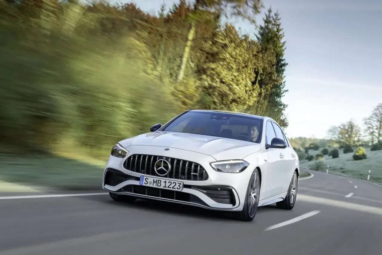 Un Mercedes-AMG blanco acelera con la fuerza de mil caballos por una carretera rural, dejando atr&aacute;s el paisaje borroso.