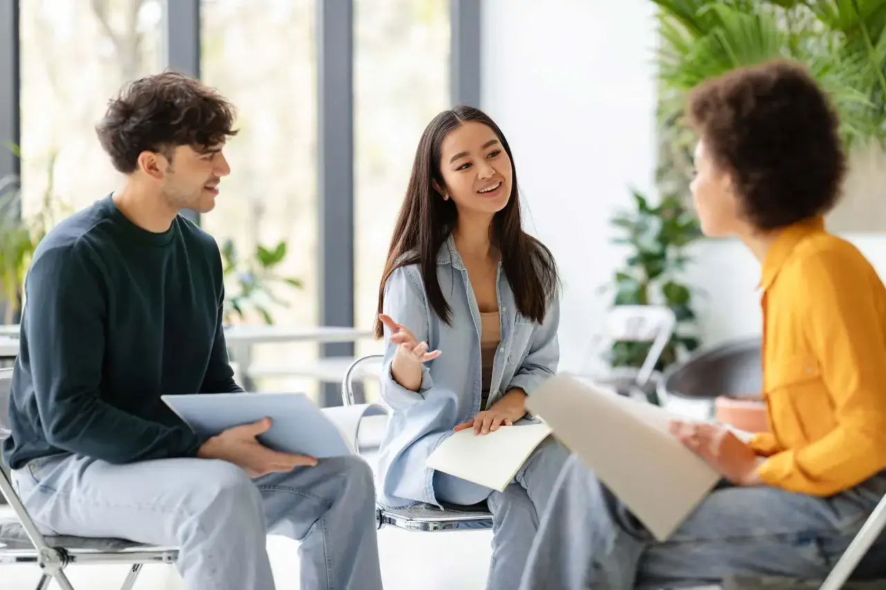 Tres jóvenes participan en conversaciones en inglés B1, compartiendo ideas y aprendiendo juntos en un ambiente relajado.
