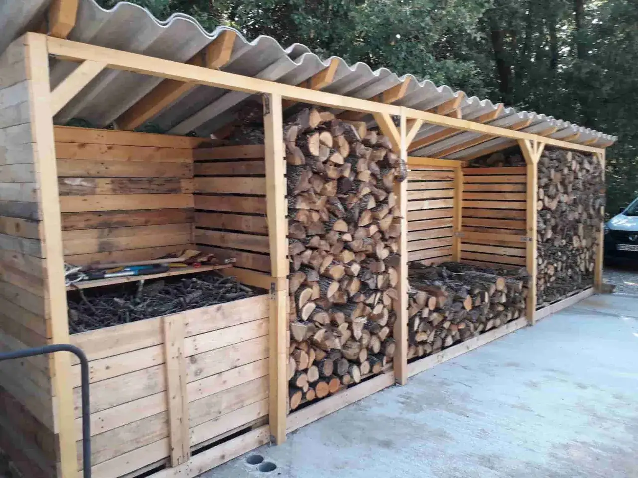 Abri en bois pour faire son bois de chauffage, rempli de bûches bien rangées.