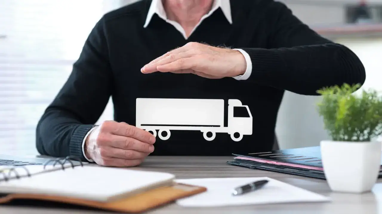 Dłonie chronią biały symbol ciężar&oacute;wki, symbolizując ubezpieczenia cargo.