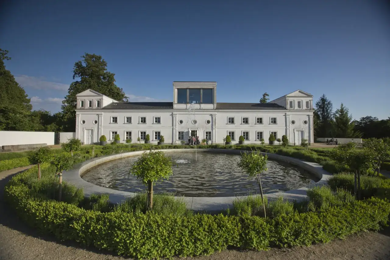 Der Schlosspark Putbus mit seinem kreisrunden Brunnen und dem weißen Gebäude im klassizistischen Stil lädt zum Verweilen ein.