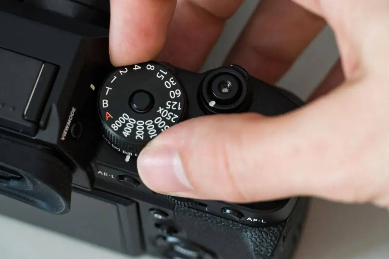 Ajustando el dial de la cámara para cambiar el ISO, un valor clave para entender que es el ISO de una cámara.