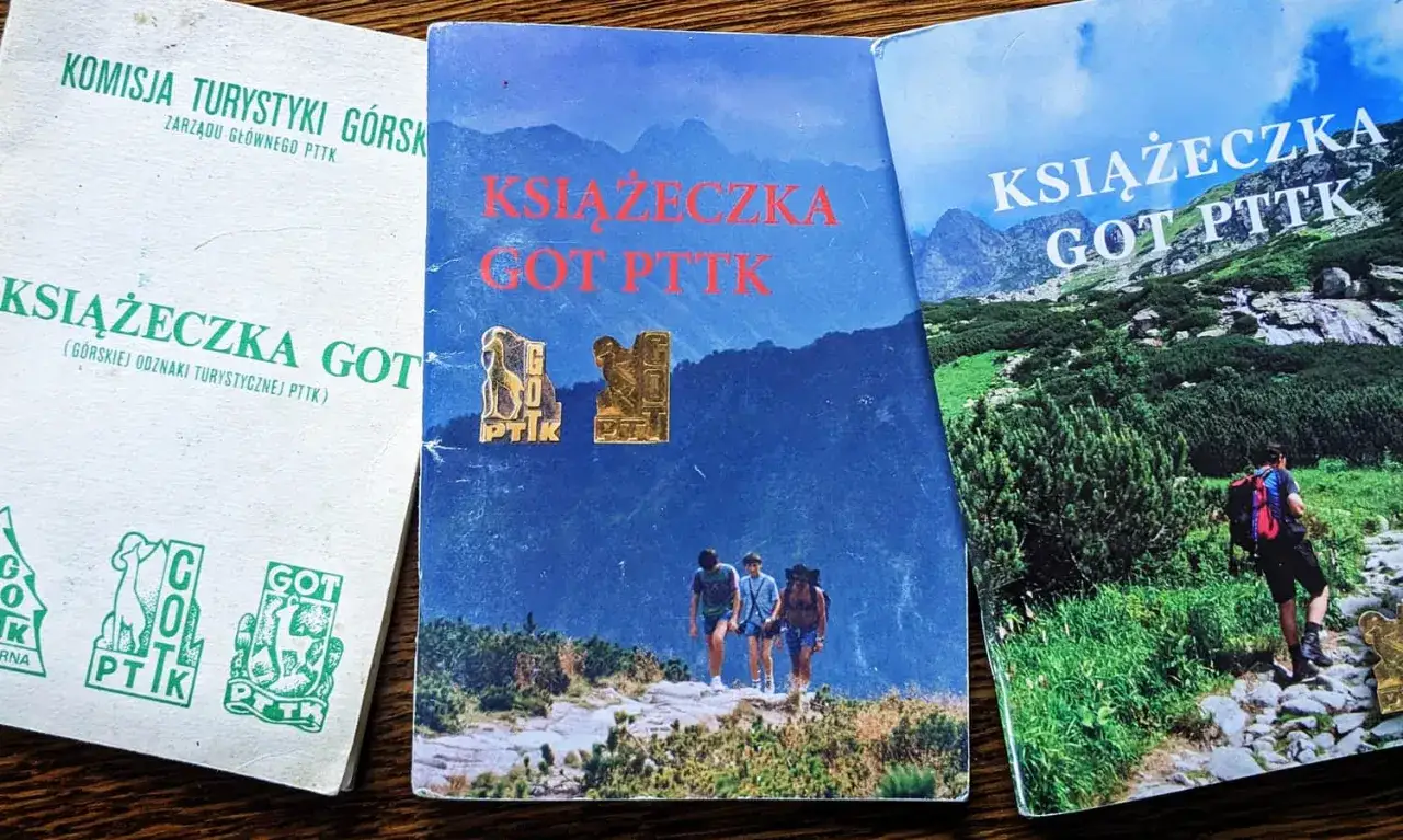Trzy książeczki GOT PTTK, dwie z widokiem gór, jedna z zielonymi odznakami.
