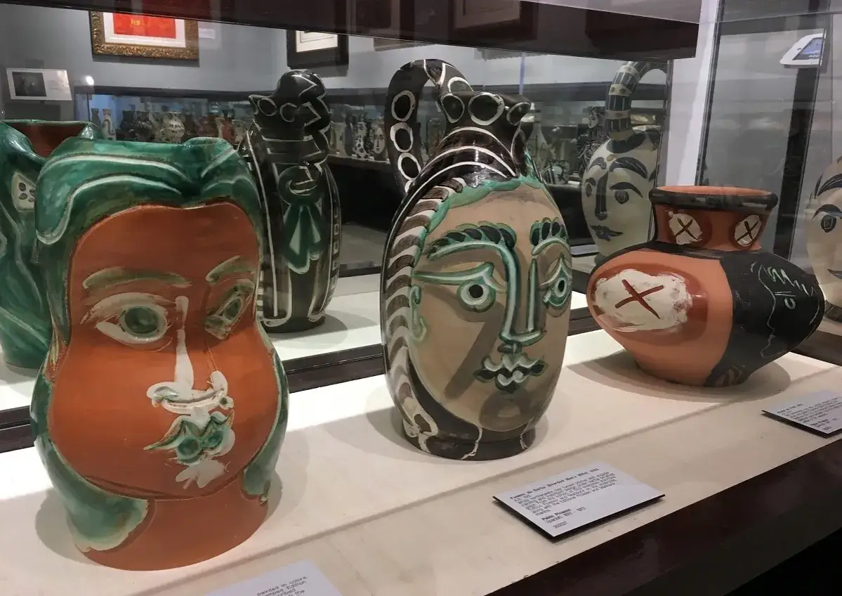 Famous ceramic pieces by Picasso, including a terracotta vase with a green and orange face, and other uniquely decorated pitchers.