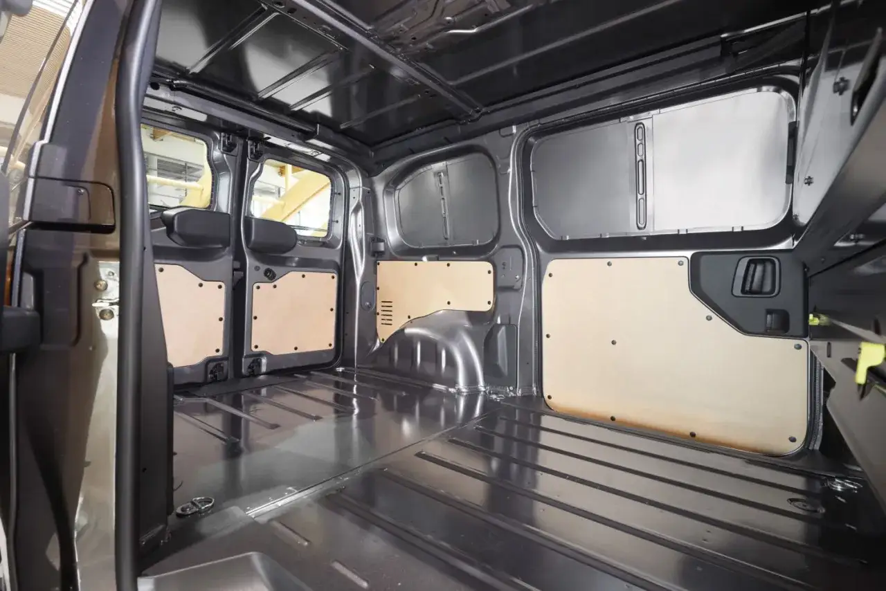 Wnętrze Toyoty Proace Long z drewnianymi panelami na ścianach i metalową podłogą, gotowe na transport.