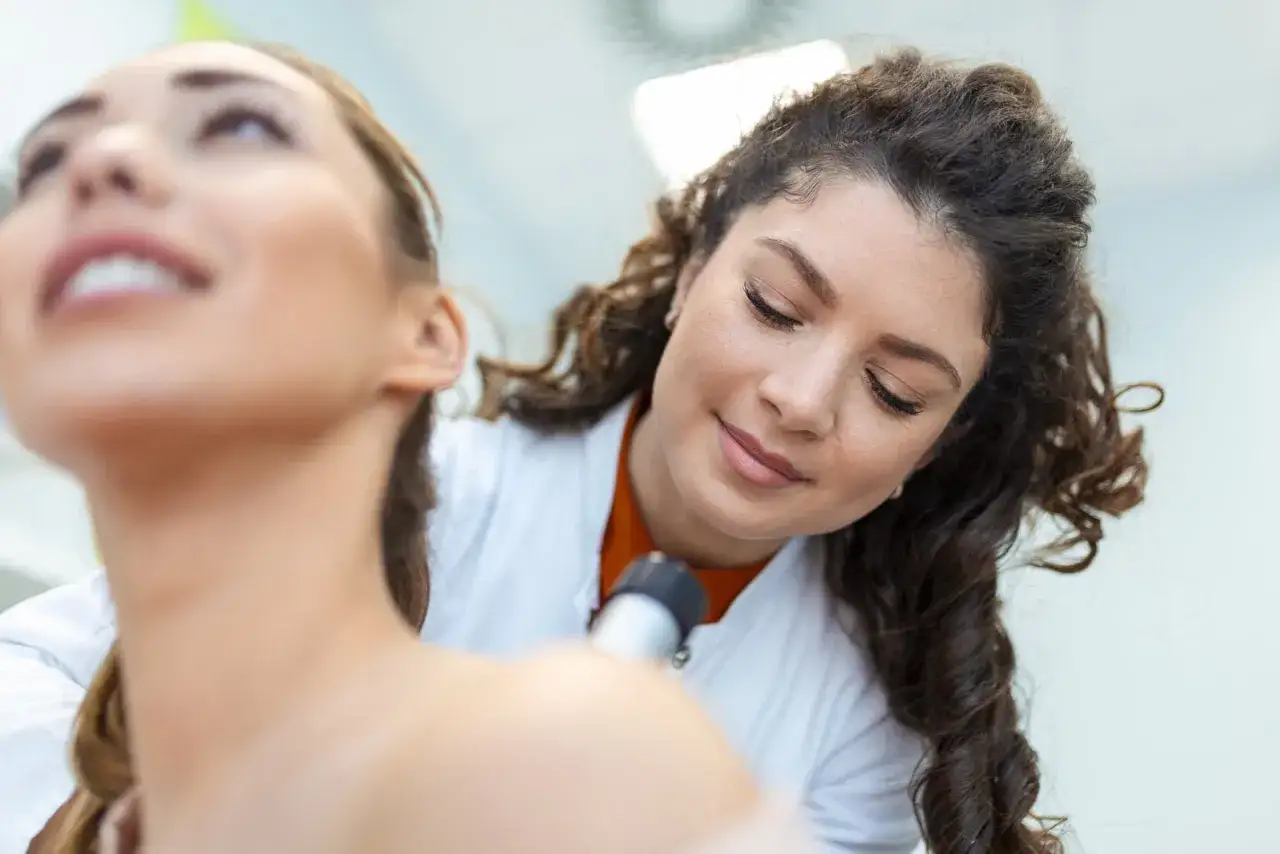 Dermatologe untersucht die Gesichtshaut eines Patienten mit einem Dermatoskop