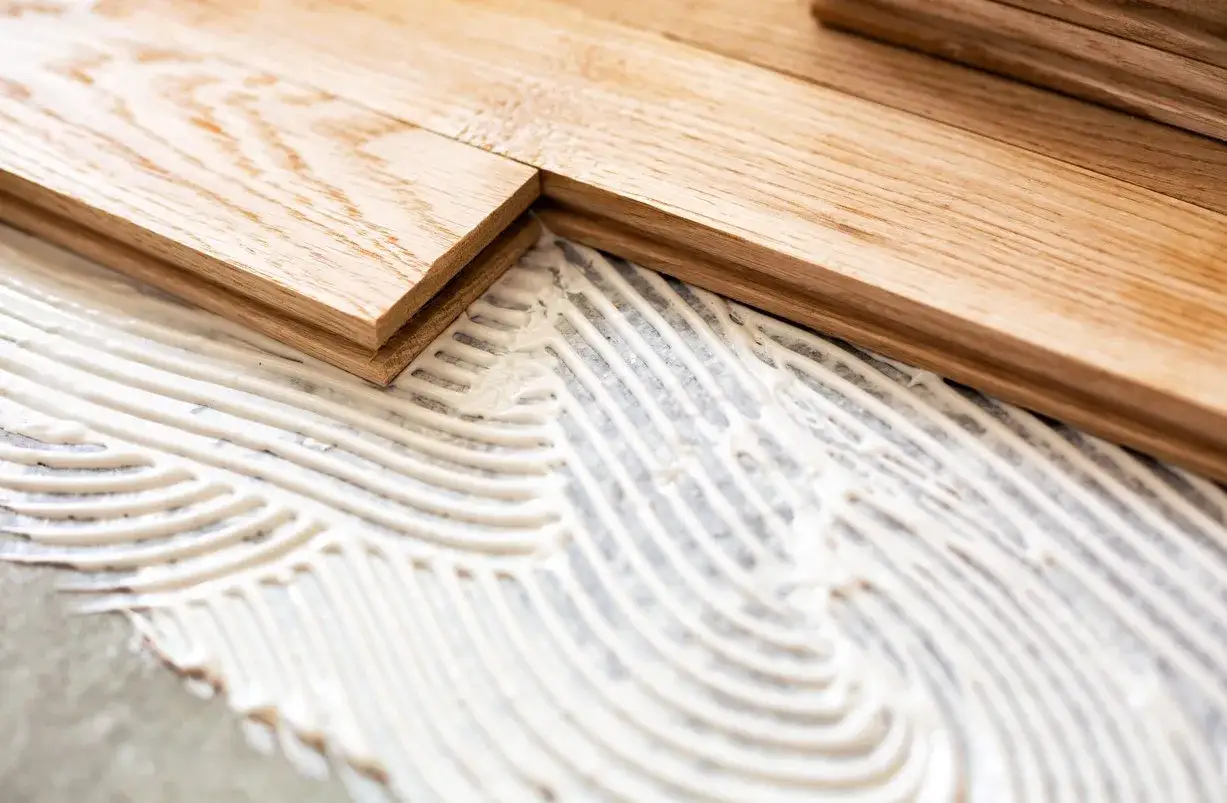 Pose de parquet en bois sur du béton avec de la colle. Les lames de bois sont prêtes à être fixées.